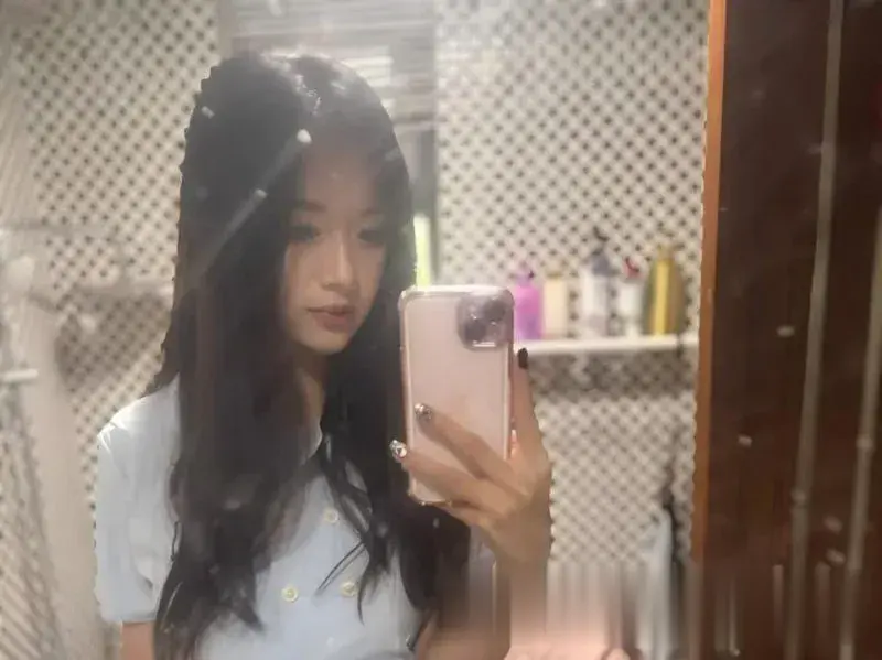 长发女孩蓝上衣浴室镜子自拍，粉色手机壳，侧脸自然表情