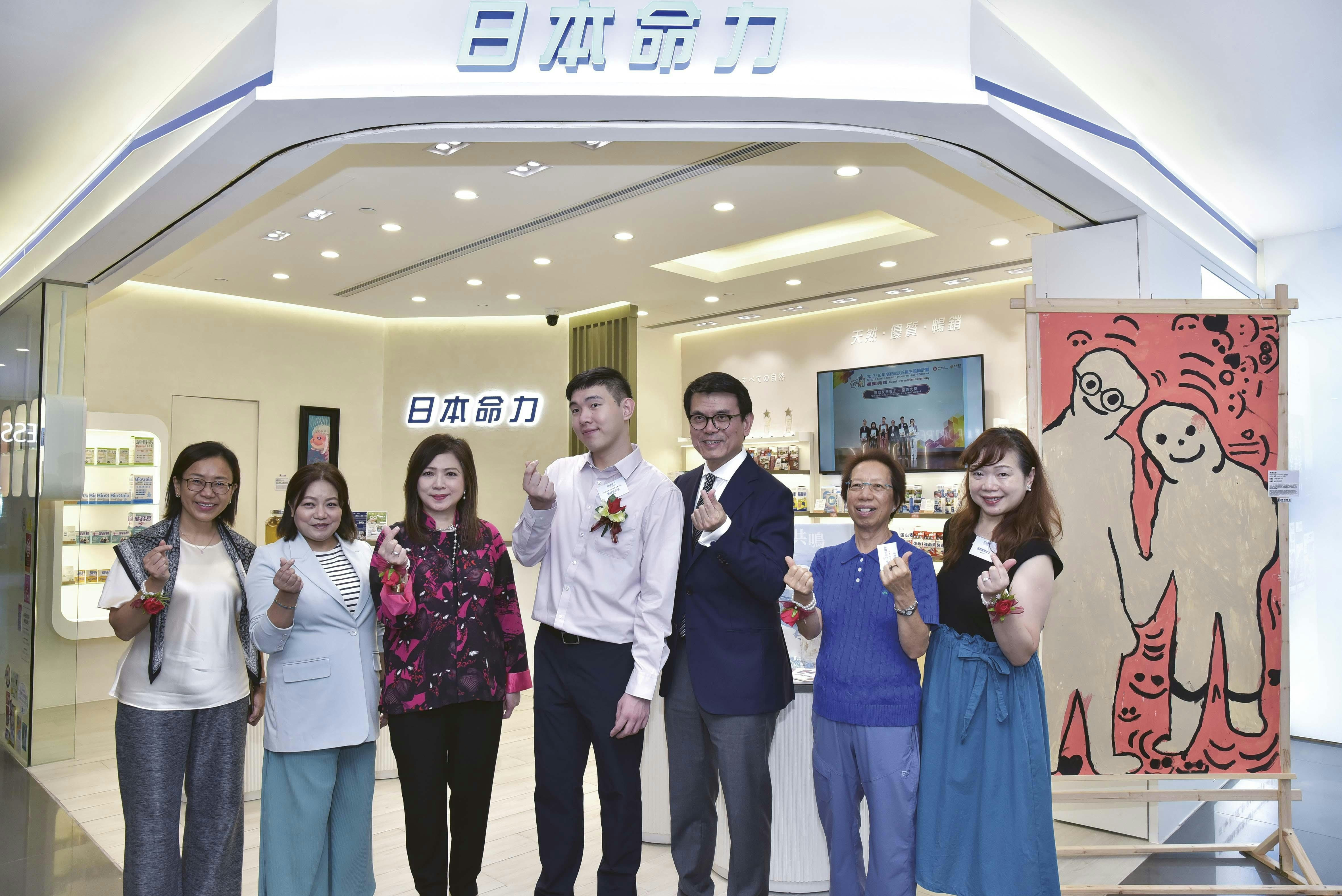 一众嘉宾与艺术家大合照（左起：香港培道小学校长陈敏仪、品牌代言人胡孟青、日本命力执行董事连舜香、匡智会艺术家张端望、匡智会执行委员会主席邱腾华, GBS, JP、世界心理卫生联盟前会长温丽友, BBS, JP、匡智会艺术家家长张邓嘉慧）