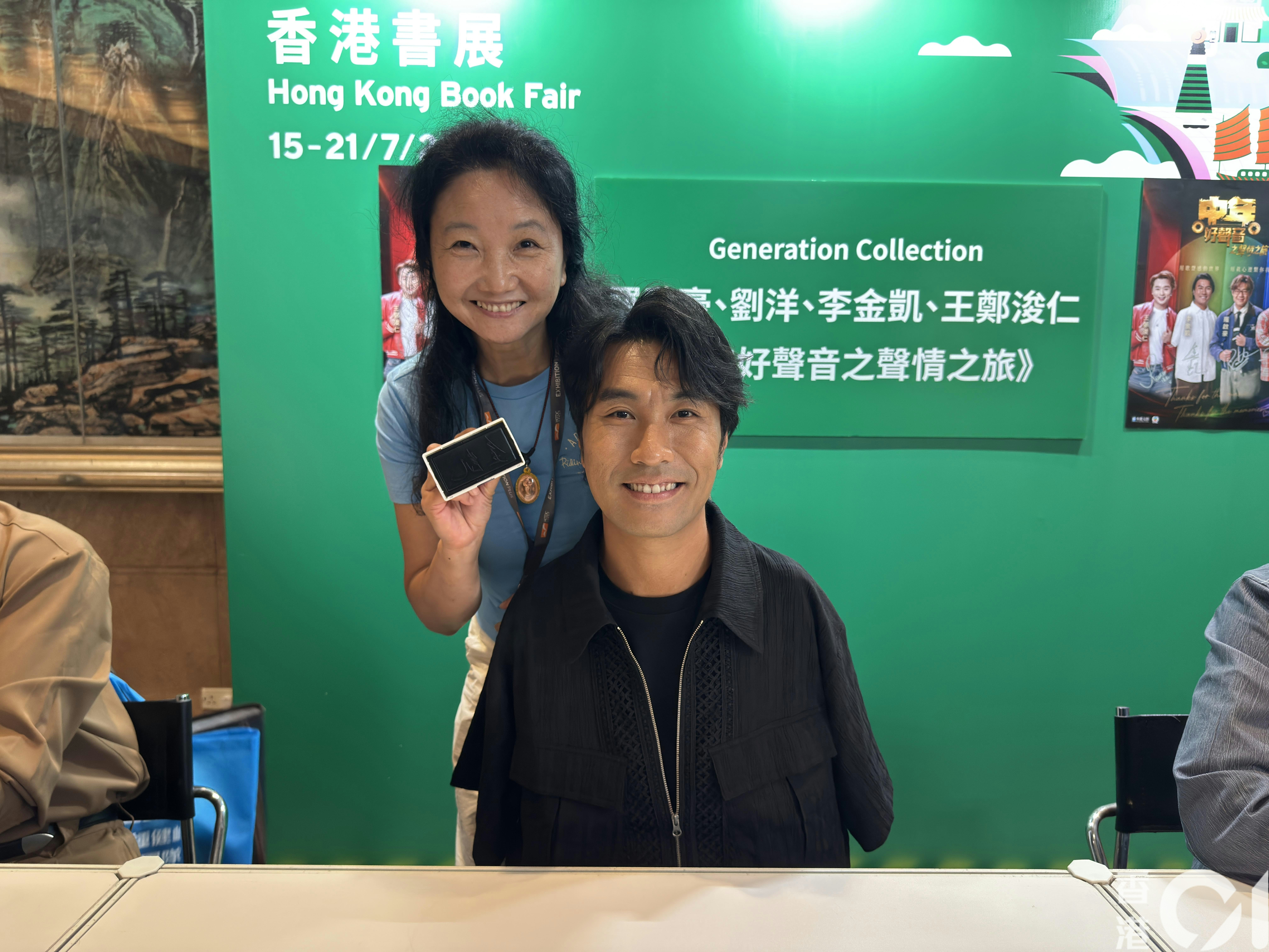 李金凯以印章代手，由姐姐协助在书上盖章。