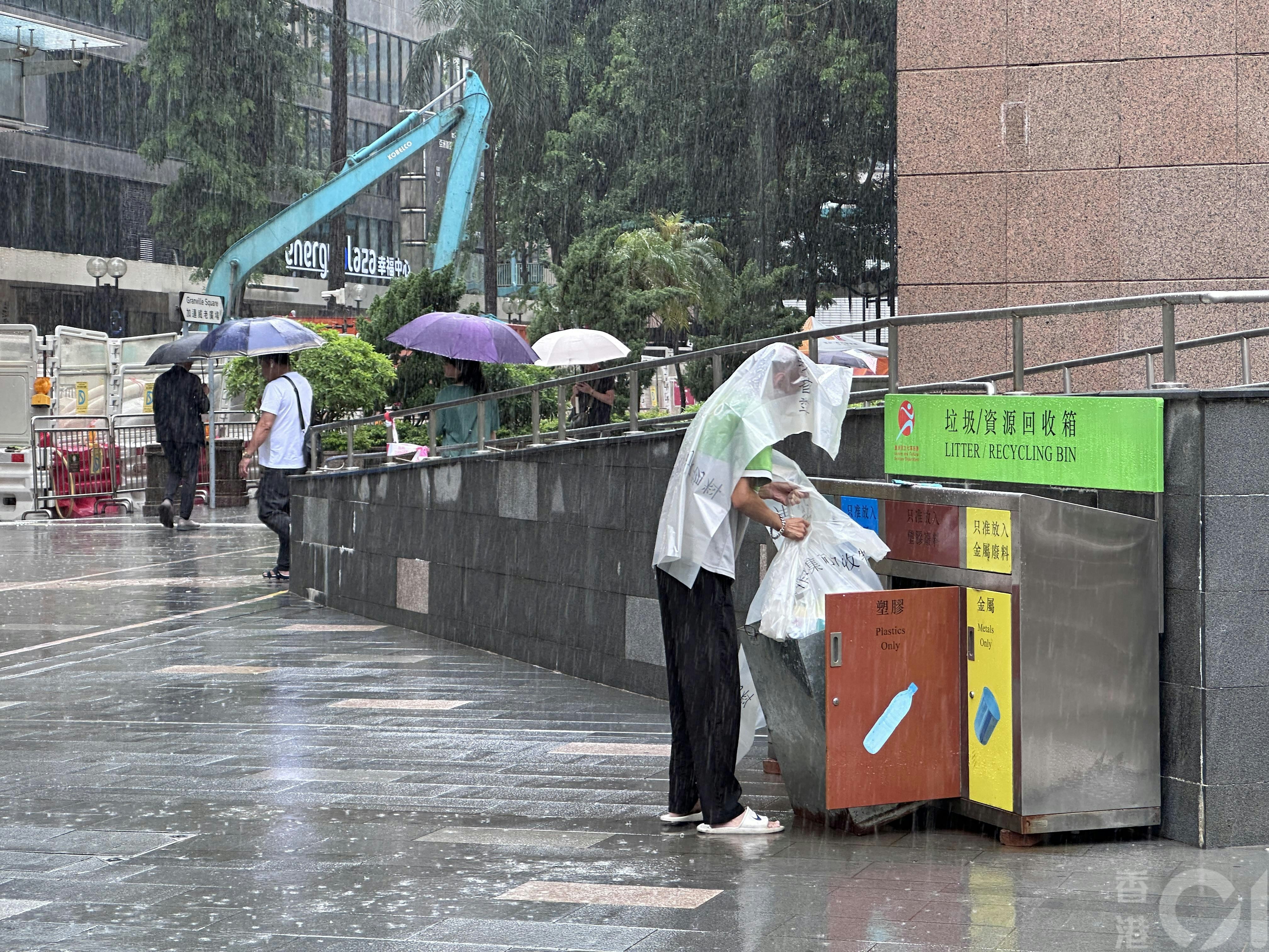 7月16日中午时分尖东忽然下大雨,有食环署外判工人拿垃圾袋暂当雨衣遮身。(倪清江摄)